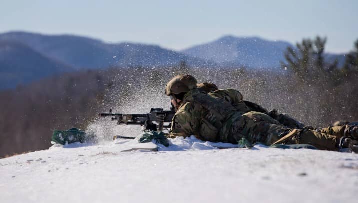 Military professionals laying down on snow wearing ECWCS