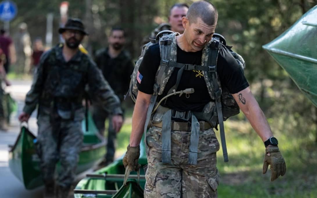 Soldier carrying canoe wearing backpack