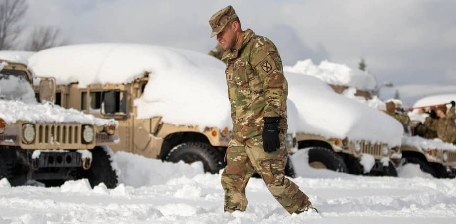 Soldier walking snow covered military vehicles