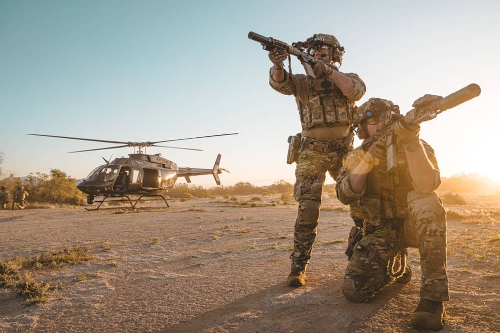 Armed soldiers in plate carriers before a helicopter