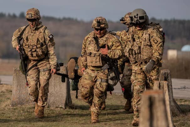 Soldiers in uniform walking across field in medical evacuation